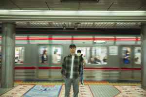 asian man standing on platform in underground