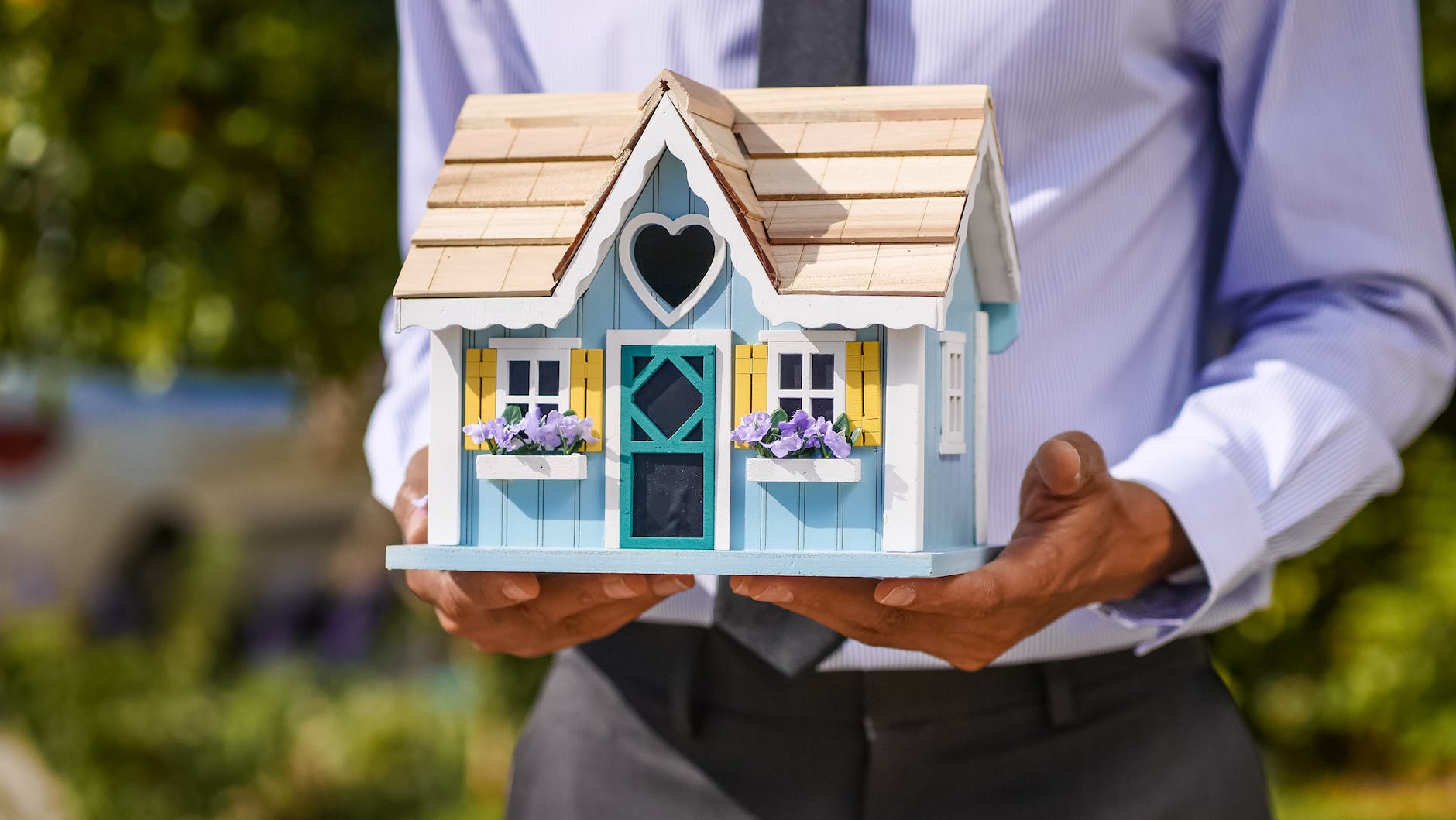 person holding a miniature wooden house